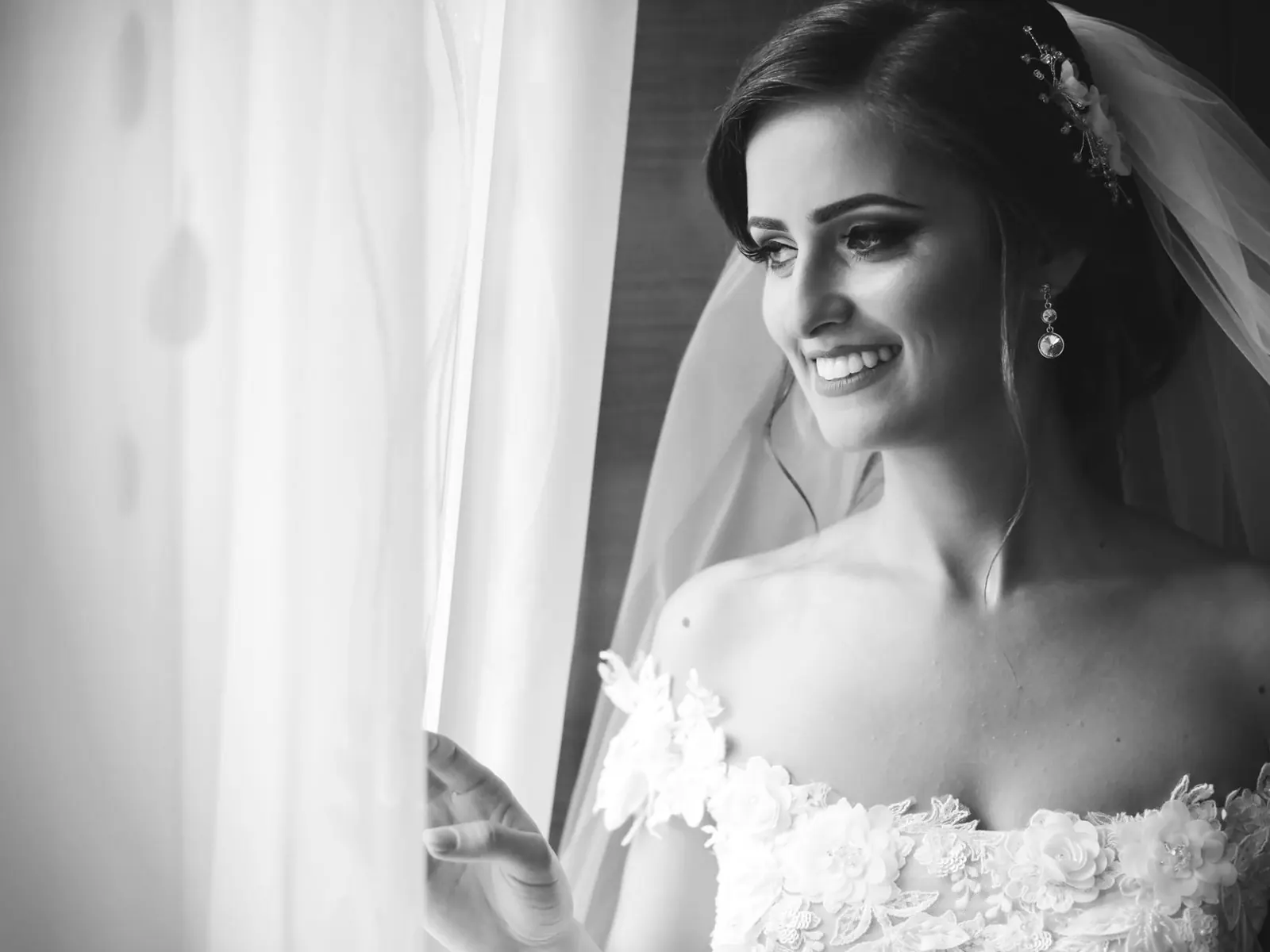 A bride smiling in the light of a window